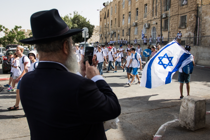 An Ultra Orthodox man takes a photo of Jewish boys walking by waving Israeli flags prior to celebrations for Jerusalem Day, June 5, 2016. The holiday marks the day when Jerusalem was reunified as part of Israel as a result of the Six-Day-War in 1967. Photo by Zack Wajsgras/Flash90 *** Local Caption *** ??? ??????? ???? ?????? ???? ?????? ????