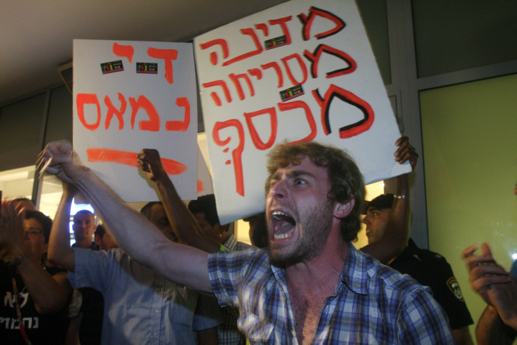 Israelis hold up signs and chant slogans as they take part in a protest march against Israeli Finance Minister Yair Lapid and the state budget during a demonstration in Tel Aviv on May 18, 2013. Thousands of Israelis took to the streets on Saturday evening to protest against the government's planned austerity measures. Photo by Roni Schutzer/Flash90 *** Local Caption *** ???? ????? ???? ???? ????? ???? ?????? ??? ????? ????? ?????